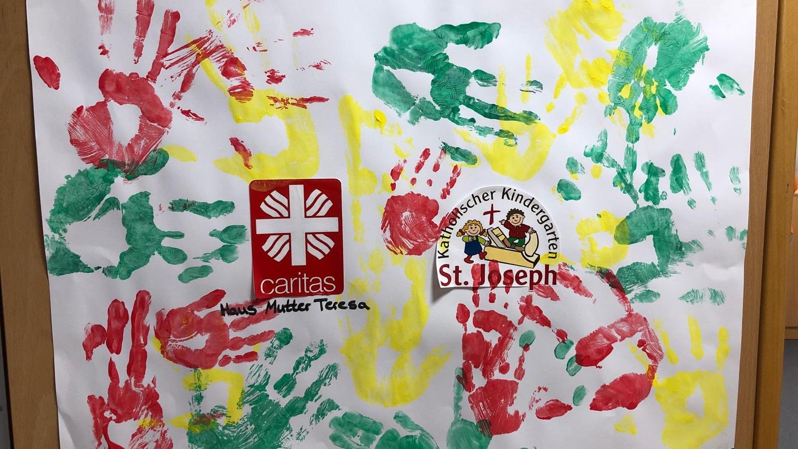 Rote, grüne und gelbe Handabdrücke der Tagesgäste auf einem Plakat.