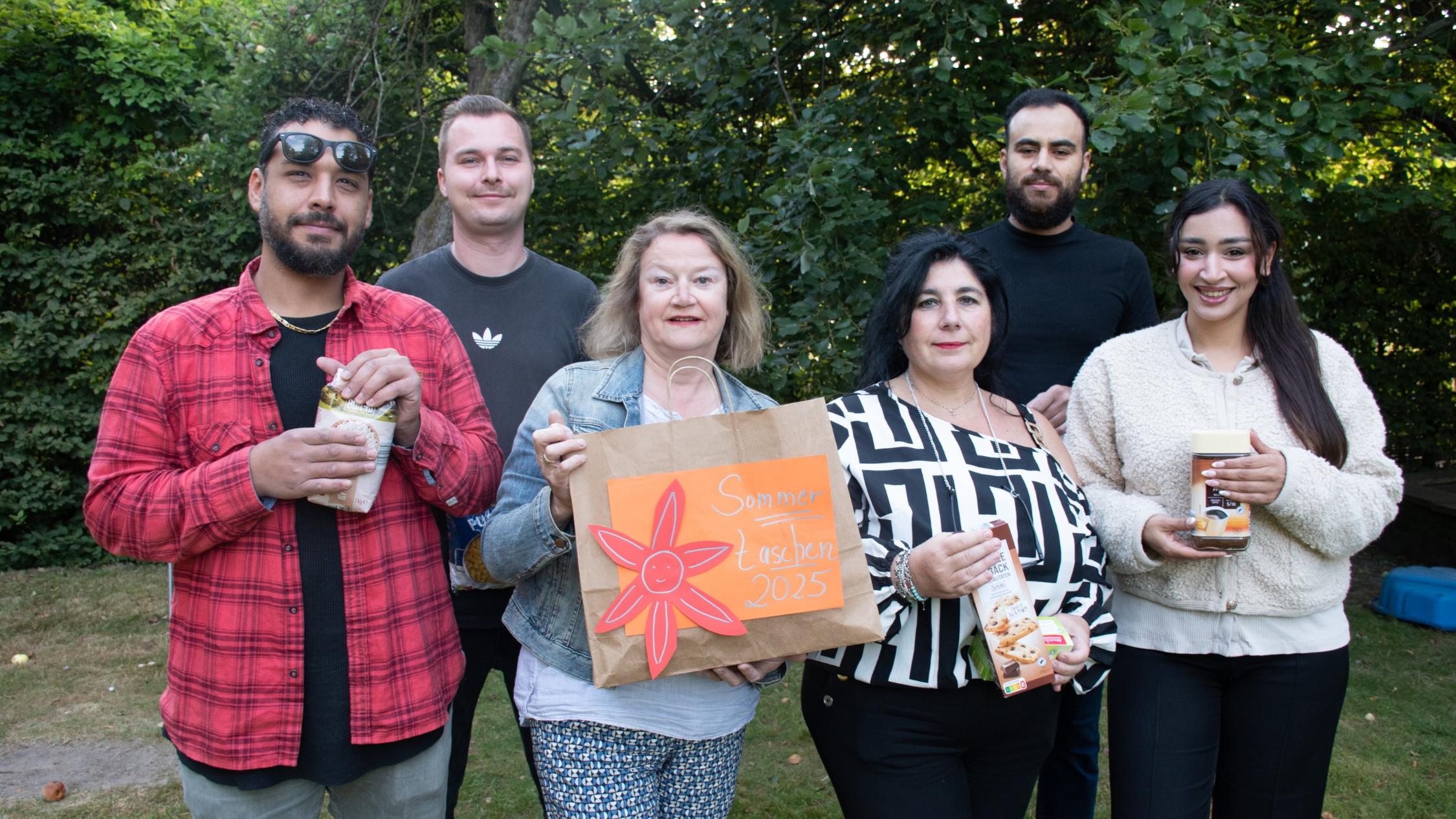 Sechs Mitarbeitende des Caritasverbandes Ahaus-Vreden präsentieren Taschen und Lebensmittel für die Sommertaschen-Aktion.