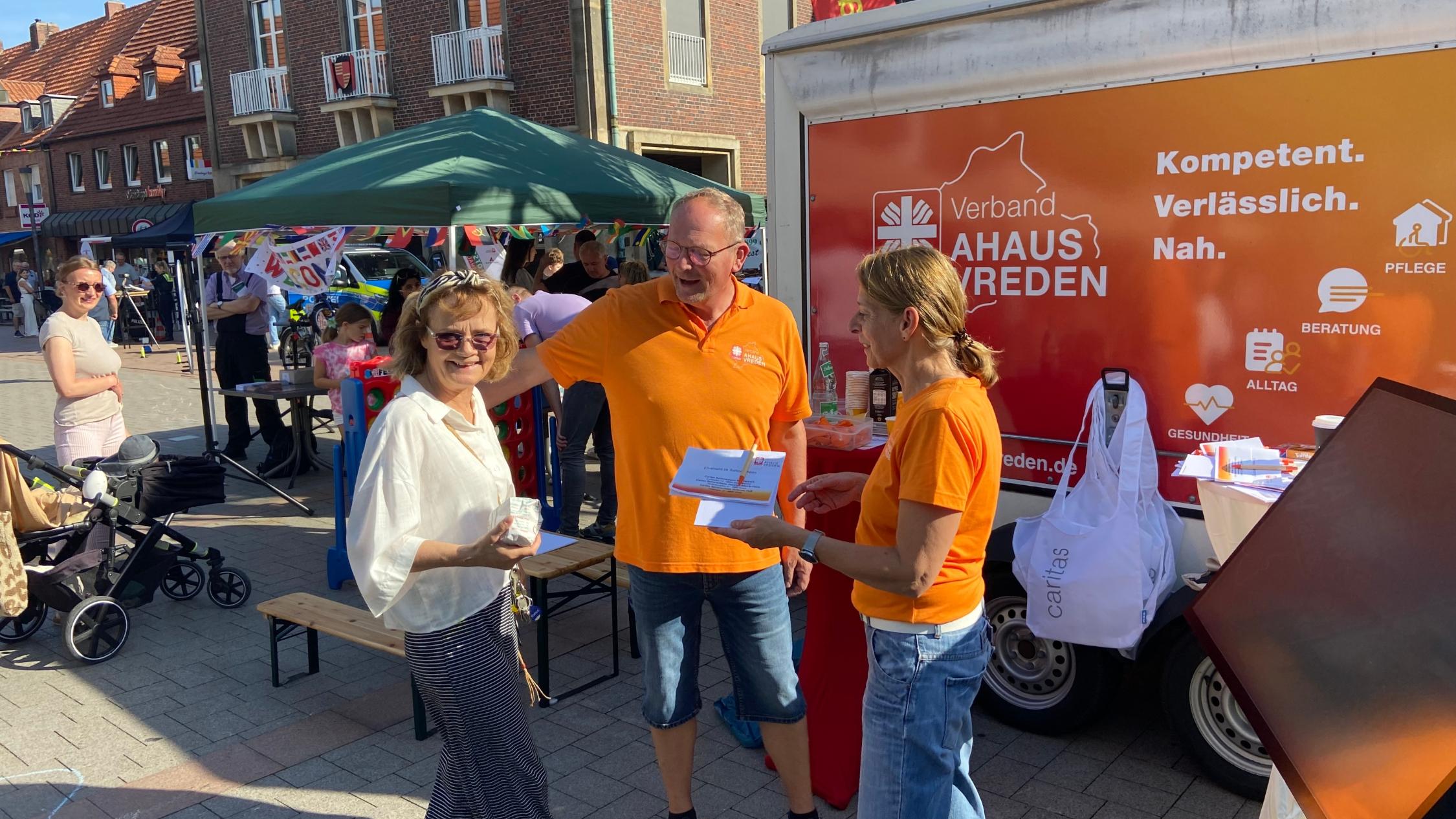 Zwei Mitarbeitende des Caritasverbandes informieren an ihrem Stand eine Frau über Möglichkeiten ehrenamtlicher Arbeit.