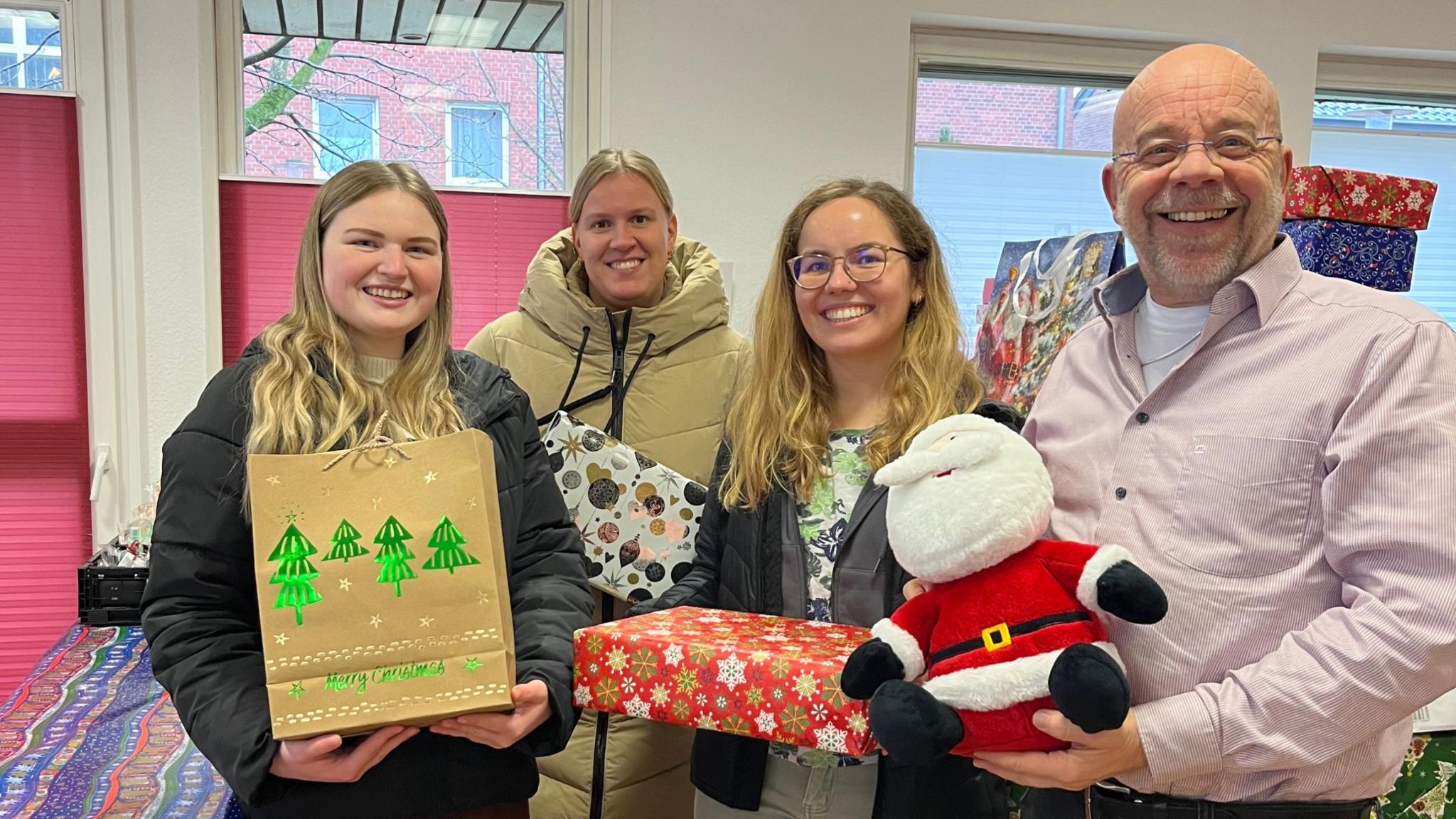 Johannes Lügering (r.) von der Ahauser Tafel und die Auszubildenden Alessia Bone, Helena Reckert und Isabell Leesker bei der Übergabe der Weihnachtspäckchen.